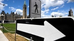 Centre Block’s Peace Tower is seen past a pedestrian crosswalk on Parliament Hill, in Ottawa, on Friday, June 17, 2022. THE CANADIAN PRESS/Justin Tang