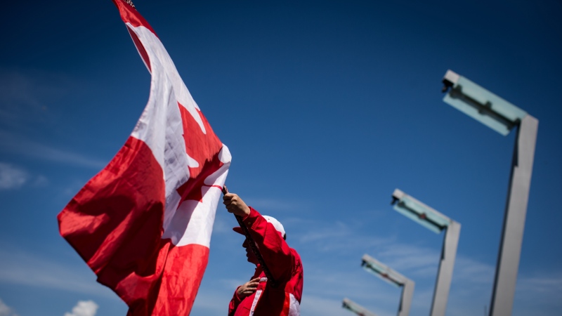 Ricky Johnson waves a Canadian flag on a hockey stick as he sings O Canada while attending Canada Day celebrations in Vancouver, on Monday July 1, 2019. THE CANADIAN PRESS/Darryl Dyck 