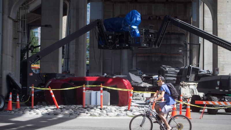 A cyclist rides past a film set for the movie "Deadpool 2" in Vancouver, B.C., Tuesday, Aug. 15, 2017. A 15-month dispute in British Columbia's film and television industry has ended with the ratification of a new contract for creative and logistical people working on productions shot in the province. THE CANADIAN PRESS/Darryl Dyck