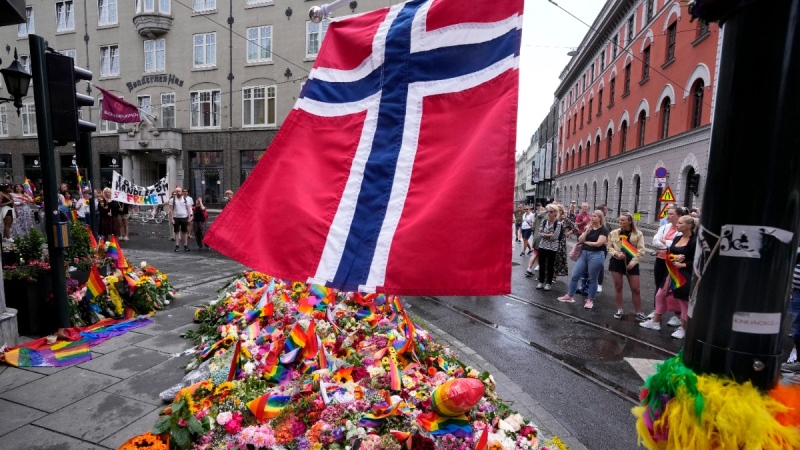 A Norwegian national flag waves over flowers and rainbow flags at the scene of a shooting in Oslo, Norway, on June 26, 2022. (Sergei Grits / AP) 