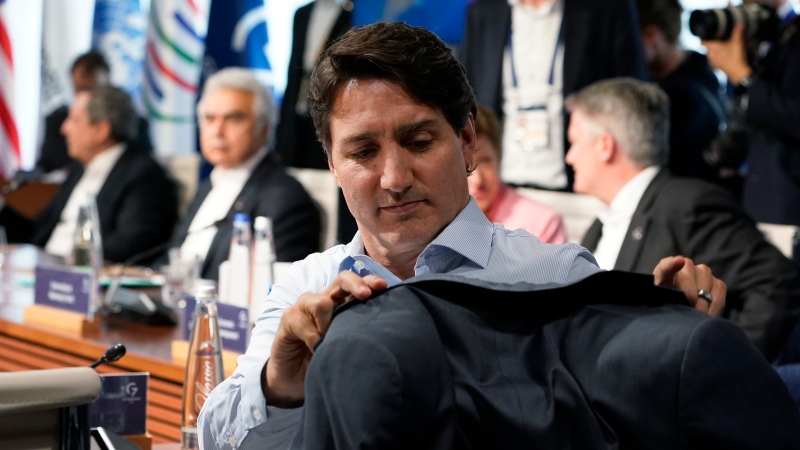 Canada's Prime Minister Justin Trudeau hangs his coat on the back of his chair as he waits for the start of a lunch with the Group of Seven leaders at the Schloss Elmau hotel in Elmau, Germany, Monday, June 27, 2022, during the annual G7 summit. Joining the Group of Seven are guest country leaders and heads of international organizations. (AP Photo/Susan Walsh, Pool)