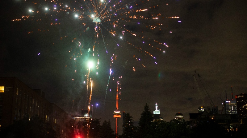 A neighbourhood Canada Day fireworks display is seen in a Toronto park, July 1, 2021, as the CN Tower is lit orange in solidarity and support of Indigenous communities across Canada. THE CANADIAN PRESS/Chris Young