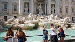 FILE - In this Friday, June 4, 2021 file photo, tourists throw their coins into the Trevi fountain as a wish to come back to the eternal city, in downtown Rome. (AP Photo/Gregorio Borgia, File)