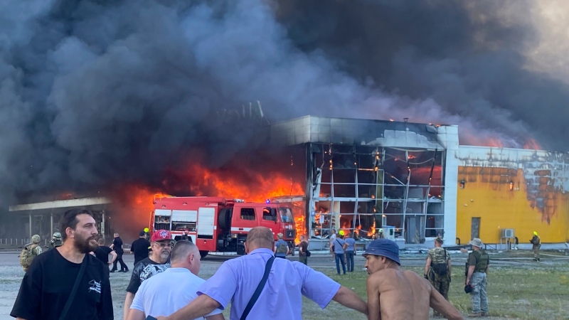 People watch as smoke bellows after a Russian missile strike hit a crowded shopping mall, in Kremenchuk, Ukraine, Monday, June 27, 2022. (Viacheslav Priadko via AP) 