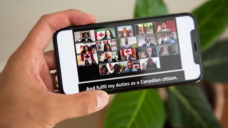 Participants raise their hands as they swear the oath to become Canadian citizens during a virtual citizenship ceremony on Canada Day, on July 1, 2020. (Justin Tang / THE CANADIAN PRESS)