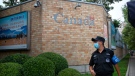 In this Aug. 6, 2020 file, a security officer wearing a face mask to protect against the coronavirus stands outside the Canadian Embassy in Beijing. (AP Photo/Mark Schiefelbein, File)