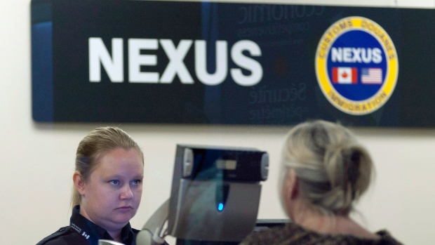 A Canada Border Services Agency officer speaks with a traveller at the Nexus office at the airport in Ottawa, Tuesday May 8, 2012.  THE CANADIAN PRESS/Adrian Wyld