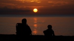 A pair of beach goers watch the sun rise over the Atlantic Ocean, Friday, June 10, 2022, in Surfside, Fla. (AP Photo/Wilfredo Lee)