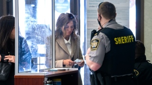 Lisa Banfield, spouse of Gabriel Wortman, puts on a facemask at Nova Scotia Provincial court in Dartmouth on Wednesday, March 9, 2022. (THE CANADIAN PRESS/Andrew Vaughan)