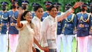 Philippine President Ferdinand Marcos Jr., right, waves beside wife Maria Louise, left, and son Sandro as they arrive at Malacanang Presidential Palace after the inauguration ceremony, on June 30, 2022. (Gerard Carreon / AP)