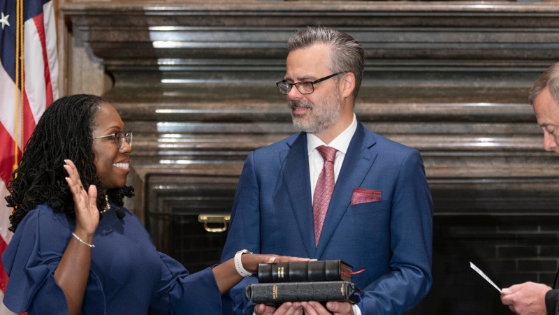 In this image from video provided by the Supreme Court, Chief Justice of the United States John Roberts administers the Constitutional Oath to Ketanji Brown Jackson as her husband Patrick Jackson holds the Bible at the Supreme Court in Washington, Thursday, June 30, 2022. (Supreme Court via AP) 