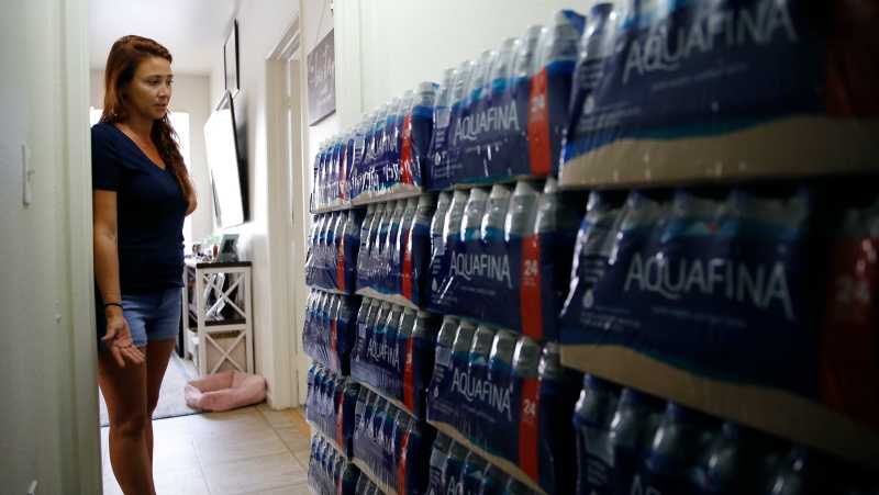 Lauren Wright, a Navy spouse whose family was sickened by jet fuel in their tap water, shows her supply of bottled water at her home in Honolulu, Friday, July 1, 2022. A Navy investigation says shoddy management and human error caused fuel to leak into Pearl Harbor's tap water last year. The leak poisoned thousands of people and forced military families to evacuate their homes for hotels. (AP Photo/Caleb Jones)