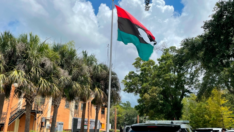 In this photo provided by Burning Spear Media, LLC, a damaged Pan-African flag flies outside the headquarters of the Uhuru Movement, a Black international socialist group based in St. Petersburg, Fla., Saturday, July 2, 2022. Earlier in the day, person using a flamethrower set fire to the flag. (Burning Spear Media, LLC via AP)