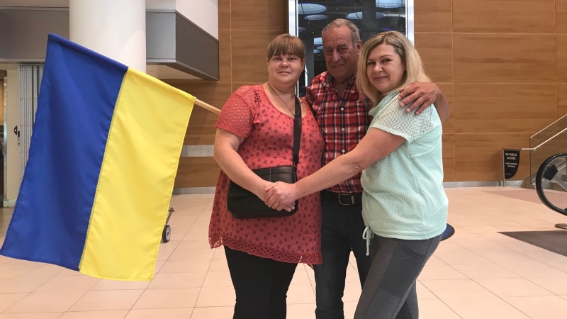 Iryna Redkina (left) is greeted by her sister Svitlana Maksymovych and husband Jan Chalmers (middle). (Source: Danny Halmarson, CTV News Winnipeg)