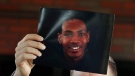 Attorney Bobby DiCello, representing the family of Jayland Walker, holds up a photograph of Walker before he and his legal team give their statements after the City of Akron's news conference at the Firestone Park Community Center on Sunday, July 3, 2022, in Akron, Ohio, where body cam video was shown of the police shooting of Walker almost a week earlier. (Karen Schiely/Akron Beacon Journal via AP)