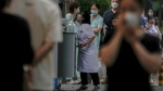 Residents line up while a pharmacist gets a throat swab for the COVID-19 test at a testing site in Beijing on July 4, 2022. (AP Photo/Andy Wong)