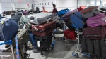 A passenger looks for his luggage among a pile of unclaimed baggage at Pierre Elliott Trudeau airport, in Montreal, Wednesday, June 29, 2022. THE CANADIAN PRESS/Ryan Remiorz