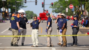 Law enforcement and members of the FBI Evidence Response team meet and gather data along Central Avenue following yesterday's mass shooting on Tuesday, July 5, 2022 in Highland Park, Ill. (Stacey Wescott/Chicago Tribune via AP)