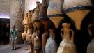 In this June 13, 2016, photo, a visitor walks by amphorae during the "Made in Roma" exhibition at the Trajan's Markets site in Rome. (AP Photo/Fabio Frustaci)