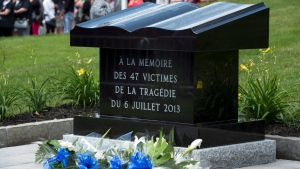 Flowers rest on the base of the stone monument in front of Ste-Agnes church in memory of the 47 victims of an oil-filled train derailment a year ago Sunday, July 6, 2014 in Lac-Megantic, Que. THE CANADIAN PRESS/Paul Chiasson