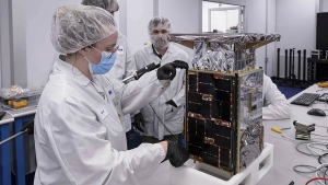 Rebecca Rogers, systems engineer, left, takes dimension measurements of the CAPSTONE spacecraft, April 2022, at Tyvak Nano-Satellite Systems, Inc., in Irvine, Calif. (Dominic Hart/NASA via AP)