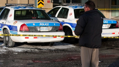 An Ottawa police investigator looks over the scene where a police officer was stabbed to death at the emergency entrance to the Ottawa Civic Hospital, Tuesday, Dec. 29, 2009. A pool of blood can be seen in the foreground with a knife, gun, notebook, glove, and flashlight. (Sean Kilpatrick / THE CANADIAN PRESS)