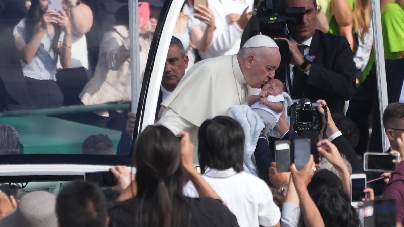 Pope Francis kisses a baby as he arrives at Commonwealth Stadium to take part in a public mass in Edmonton, July 26, 2022, . THE CANADIAN PRESS/Nathan Denette