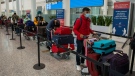 Passengers from New Delhi wait in long lines for transportation to their quarantine hotels at Pearson Airport in Toronto, April 23, 2021. THE CANADIAN PRESS/Frank Gunn