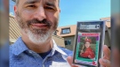 Allie Tarantino holding a baseball card featuring a very young Mark Zuckerberg grinning in a red jersey and gripping a bat. (Shira Tarantino via AP)