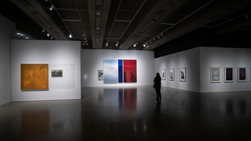 A person walks amongst art at 'Robert Houle: Red is Beautiful' at the Art Gallery of Ontario, in Toronto, on Thursday, December 2, 2021. (THE CANADIAN PRESS/Chris Young)