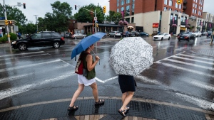 People holding umbrellas make their way along Bank Street, in Ottawa, July 24, 2022 THE CANADIAN PRESS/Spencer Colby