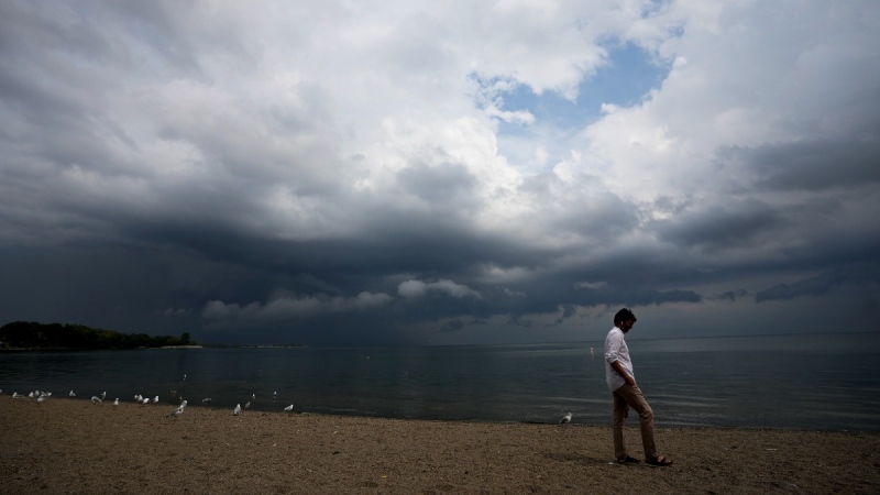 A person looks out over Lake Ontario as a thunderstorm rolls through in Toronto on August 4, 2022. (Nathan Denette / THE CANADIAN PRESS)