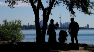 A family take pictures in the shade on a hot day in Toronto on June 23, 2022. (Nathan Denette / THE CANADIAN PRESS)