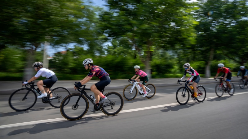 Yang Lan, second from left, and other members of the Qiyi bicycle club ride along a rural road during a group ride through the Baihe River Canyon in the northern outskirts of Beijing, Wednesday, July 13, 2022. (AP Photo/Mark Schiefelbein)
