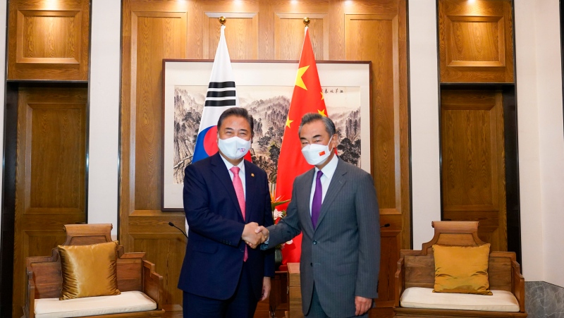 In this photo provided by South Korea Foreign Ministry, South Korean Foreign Minister Park Jin, left, shakes hands with his Chinese counterpart Wang Yi prior to their meeting in Qingdao, China, Tuesday, Aug. 9, 2022. (South Korea Foreign Ministry via AP)