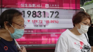 People wearing face masks walk past a bank's electronic board showing the Hong Kong share index in Hong Kong, Aug. 10, 2022. (AP Photo/Kin Cheung)