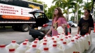 Vanessa Correa, left, and Gigi Fiske, right, pass out gallons of milk at a food distribution held by the Farm Share food bank in Miami, Fla., on July 20, 2022. (Lynne Sladky / AP)