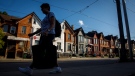 A person walks by a row of houses in Toronto on July 12, 2022. (THE CANADIAN PRESS/Cole Burston)