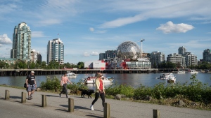 People walk along the False Creek seawall in Vancouver. (Shutterstock)