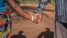 In this photo taken Wednesday, Nov. 18, 2015 a 15-year-old pregnant girl holds hands with her 20-year-old husband-to-be in Guibombo, some 40 kilometers from the city of Inhambane, Mozambique. (AP Photo/Shiraaz Mohamed)