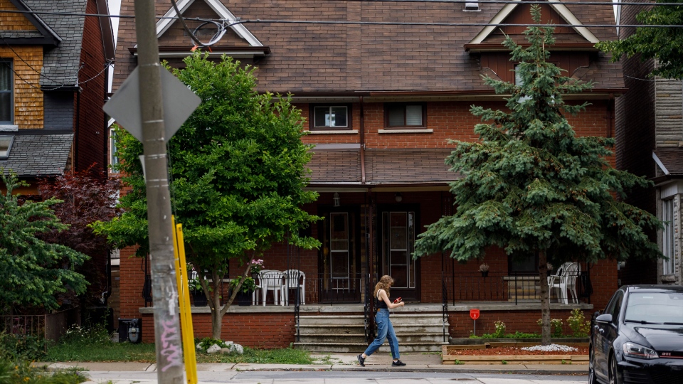 A person walks by a row of houses in Toronto