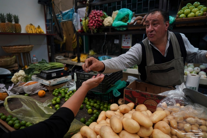 A vegetable vendor gives change to a customer at Medellin Market in Mexico City, Monday, May 9, 2022. Mexico's central bank on Thursday raised its interest rate to the highest level in the 16 years since comparable bank policies went into effect. (AP Photo/Fernando Llano)