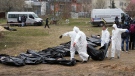 Men wearing protective gear carry a dead body during the exhumation of killed civilians in Bucha, outskirts of Kyiv, Ukraine, Friday, April 8, 2022. (AP Photo/Efrem Lukatsky, FILE)