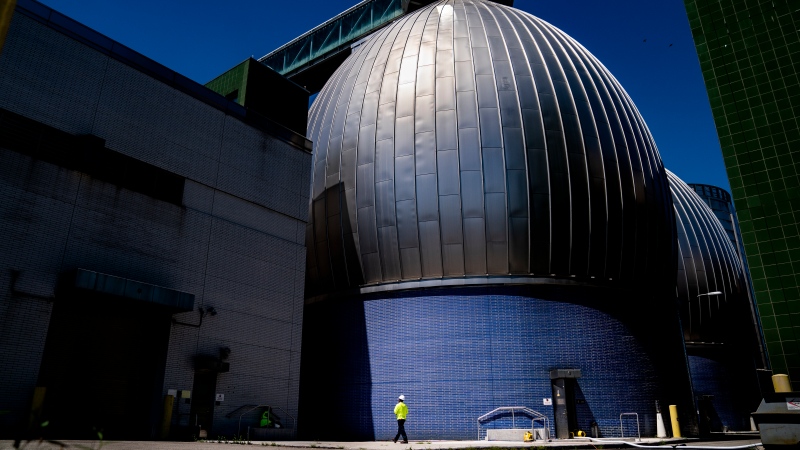 A worker walks alongside the Newtown Creek Wastewater Treatment Plant's array of digester eggs, Friday, Aug. 12, 2022, in the Greenpoint neighborhood of the Brooklyn borough of New York. (AP Photo/John Minchillo)