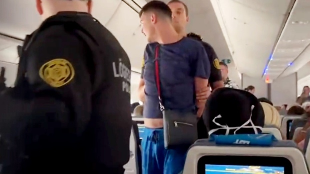 Police in Iceland escort a passenger off a LOT Airlines flight after an incident mid-air. (Supplied)