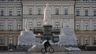 A man rides a bicycle backdropped by a statue of Grand Princess Olga of Kyiv, in the process of being covered in sandbags to avoid damage from potential shelling, in Kyiv, Ukraine, March 28, 2022. (AP Photo/Vadim Ghirda)
