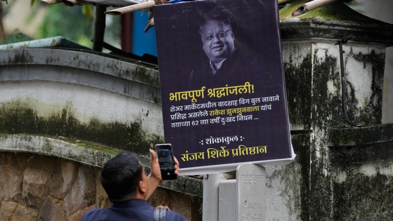 A man takes picture of a poster paying homage to veteran stock market investor and Indian billionaire Rakesh Jhunjhunwala displayed outside his residence in Mumbai, India on Aug.14, 2022. Jhunjhunwala, nicknamed India's own Warren Buffett, died Sunday in Mumbai city, Press Trust of India news agency reported. He was 62. (AP Photo/Rafiq Maqbool)