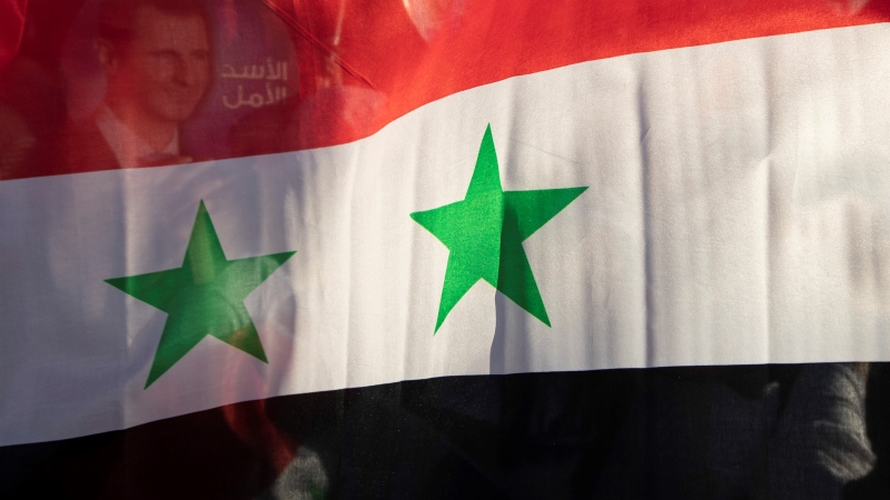 In this May 23, 2021, file photo, the Syrian national flag is displayed at a gathering at Omayyid Square in the Syrian capital Damascus, Syria. (AP Photo/Hassan Ammar, File)