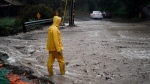 A resident stands on a flooded road during a rain storm in Silverado Canyon, Calif., March 28, 2022. (AP Photo/Jae C. Hong)