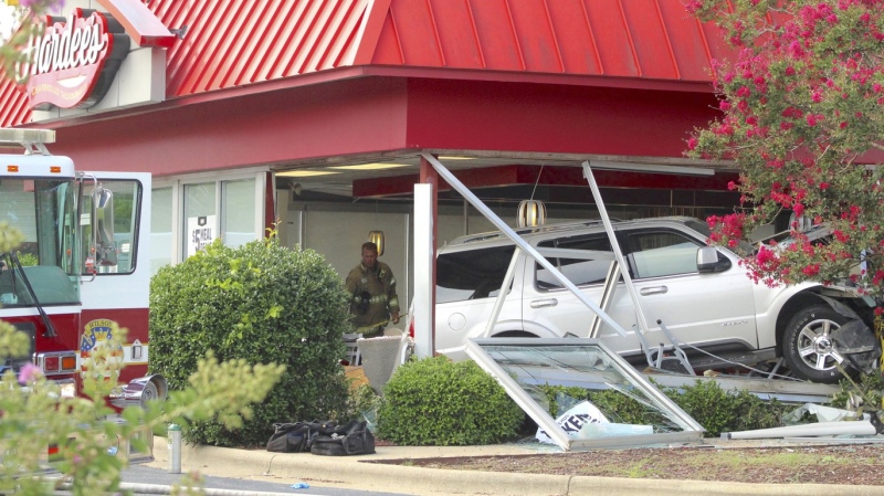 A firefighter stands behind a sport utility vehicle that crashed into a Hardee’s restaurant, Aug. 14, 2022, in Wilson, N.C. (Drew C. Wilson/The Wilson Times via AP)